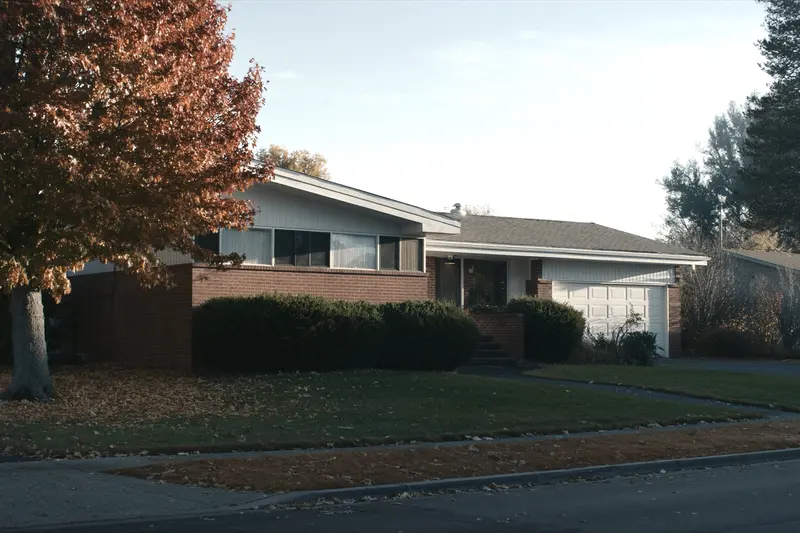 A brick ranch house in autumn light, a red maple in the front yard and a white garage door at the right